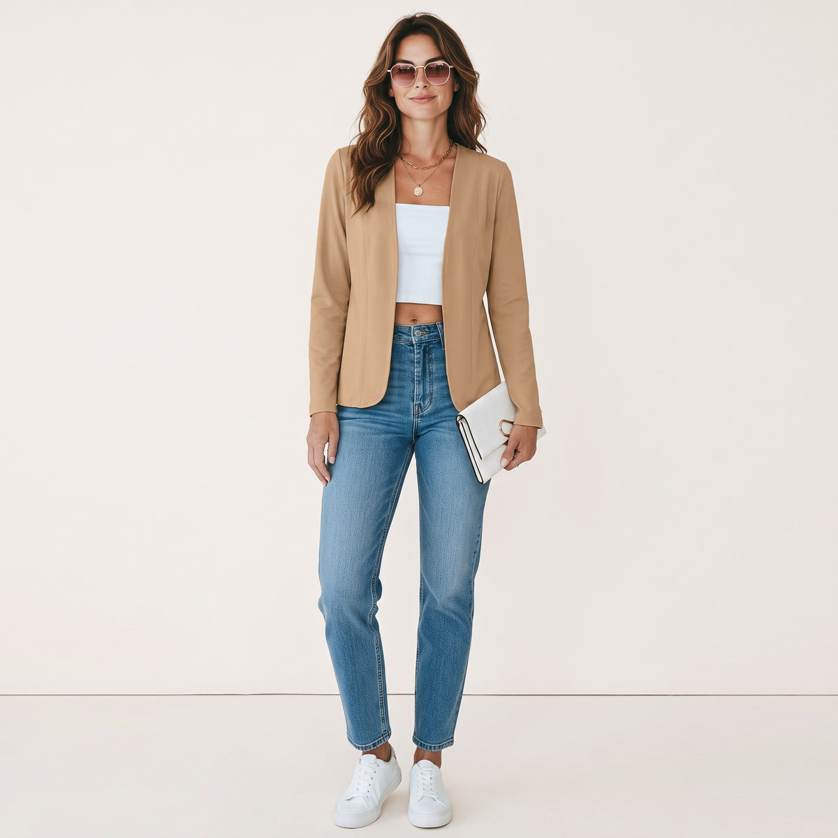 Model draagt een beige Crisstians fashionstore kraagloos vestjasje in slim fit met jeans, witte top en sneakers.