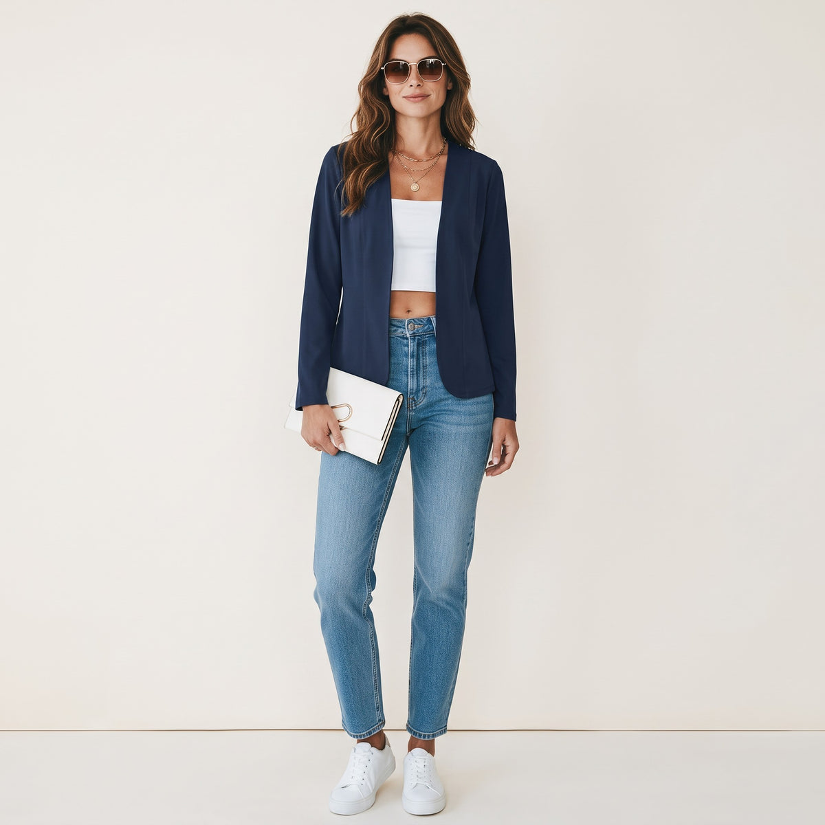 Crisstians fashionstore donkerblauw getailleerd vest zonder kraag gedragen door een vrouw met jeans en witte sneakers