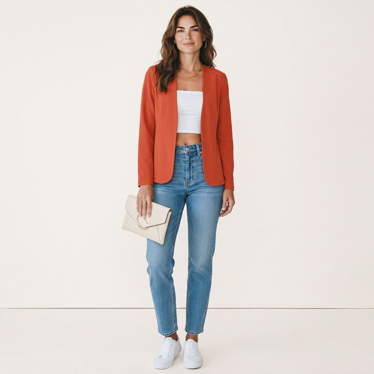 Model draagt een oranje Crisstians fashionstore kraagloos vestjasje met een slanke pasvorm en witte top.